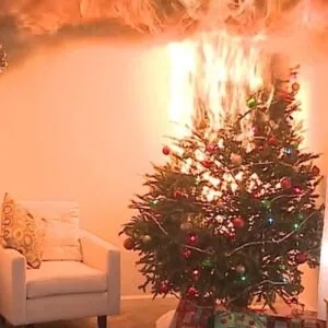 Decorated Christmas tree with red and green ornaments next to white armchair in warm-lit room