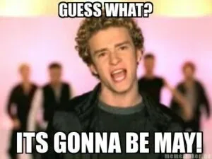 Person with curly hair in black shirt with text reading "Guess what?" and "It's gonna be May!"