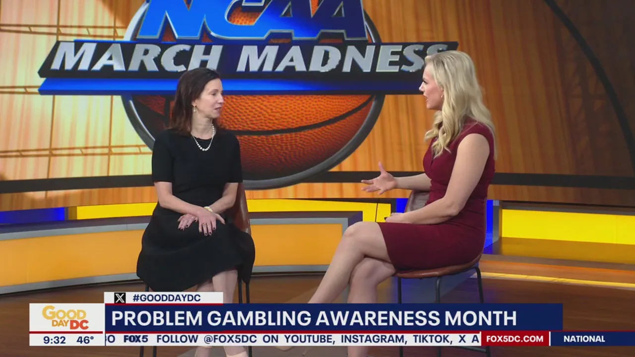 Two women sit facing each other on a TV set with March Madness basketball graphics and branding visible in the background during a segment about problem gambling awareness.