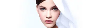 Woman with pale skin and defined makeup wearing white fabric headwrap on white background